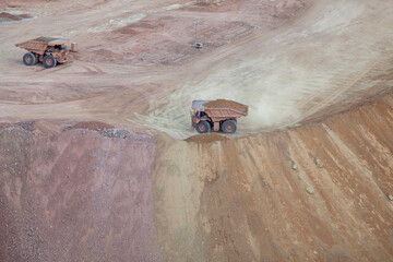 Two dump trucks from above looking down on dirt landscape © Cavan