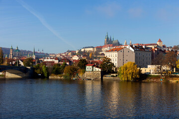 Fototapeta premium Autumn colorful Prague Lesser Town with gothic Castle above River Vltava in the sunny Day, Czech Republic