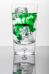 Green drops in water glass with ice