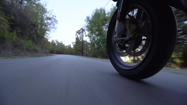 Motorcycle ridind on a road in nature. Close up wheel on a bumpy asphalt road. Speed up video