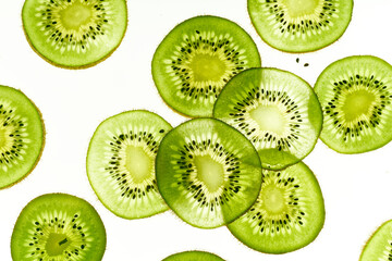 Pattern with backlit kiwi fruit slices on white background