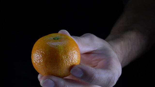 Pelando una mandarina a mano con plano en detalle con fondo negro en resoluci&oacute;n 4k