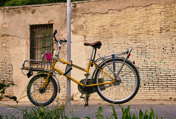 Fototapeta na wymiar A vintage yellow bicycle parked in an old street in the clot neighborhood in Barcelona