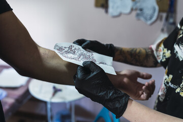 Female tattoo artist tattooing a client's arm