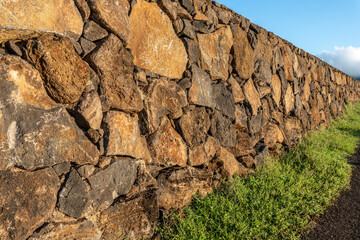 Lava rock wall made of orange and yellow basalt stone piled and fitted together 2, Poipu Kauai