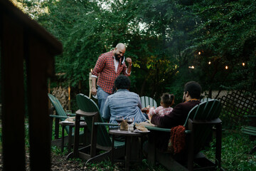 Friends gathered for evening party in backyard around firepit