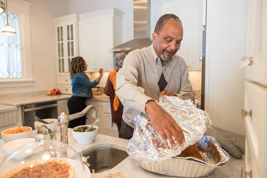 Black granddad preparing turkey for Thanksgiving dinner