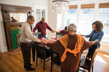 Black multigenerational family praying and blessing the food for Thanksgiving holiday meal