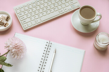 Cozy woman workplace with chrysanthemum flowers, blank notepad, cup of coffee and candle. Top view, flat lay