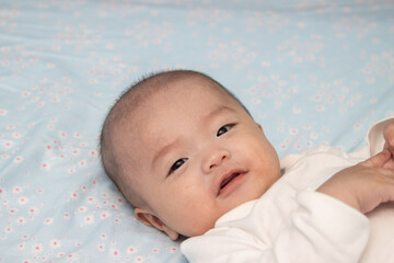 Happy Smiling face Asian Chinese baby boy during lying on bed. Happy Newborn child relaxing in bed