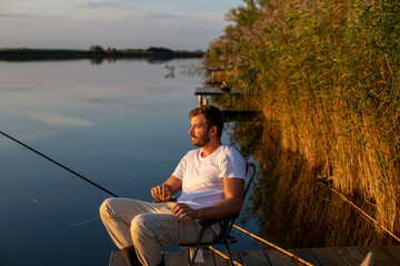 Handsome man fishing on a lake at the sunset.