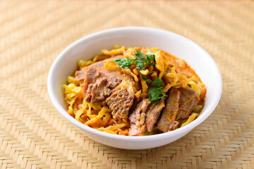 Northern Thai food (Khao Soi), Spicy curry noodles soup with beef in a bowl on woven bamboo sheet