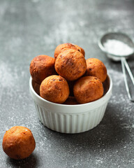 Cottage cheese round donuts in a white bowl on the dark table. Close Up. Tea time. Vertical Orientation