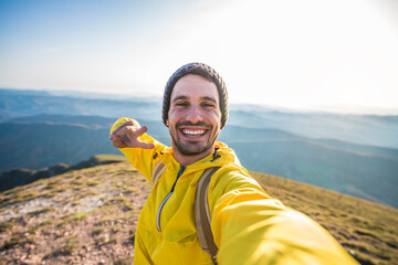 Handsome hiker taking a selfie on the top of the mountain - Happy man with backpack smiling at the...