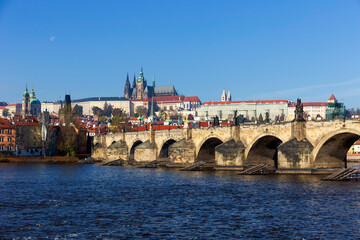 Obraz premium Autumn colorful Prague Lesser Town with gothic Castle and Charles Bridge above River Vltava in the sunny Day, Czech Republic