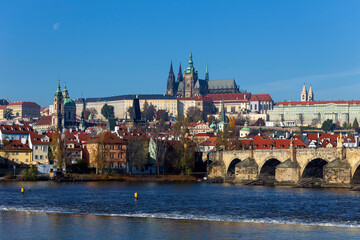 Autumn colorful Prague Lesser Town with gothic Castle and Charles Bridge above River Vltava in the sunny Day, Czech Republic