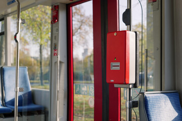 Selected focus at Red public transportation ticket stamp or validation ticket machine in front of automatic door of light rail tram in Düsseldorf, Germany.