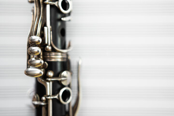 Obraz premium Closeup of clarinet keys against blurry staff paper background