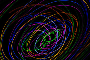 Multi color light painting photography, swirl and curve of blue, green and red light against a black background.