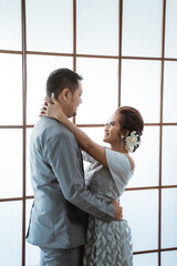 Portrait men and women wearing wedding dresses and suits standing by the window