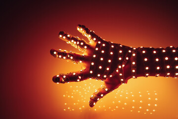 human hand covered with orange led lights, illuminated background