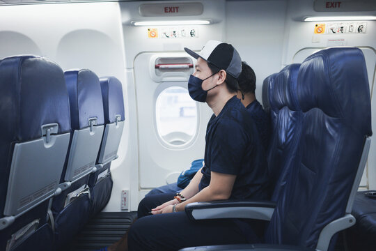 Asian traveler man wearing face mask inside airplane during flight.