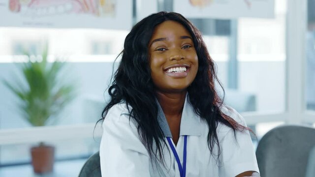 Portrait of beautiful african american woman young intern smiling positively at camera working in hospital reception. Medical employee. Student.
