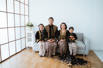 Portrait of a happy family wearing traditional Javanese clothes. concept of family photo Javanese traditional clothes in the living room