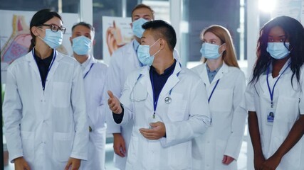 Multi-cultural diverse medical staff of doctors and assistants removing face masks smiling celebrating end of quarantine coronavirus victory applauding teamwork hospital office concept. - Powered by Adobe