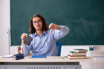 Young male teacher in front of green board