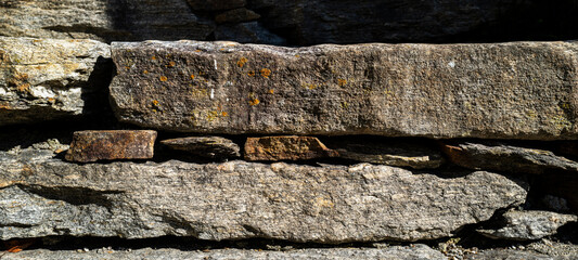 Stacked rocks, smaller rocks holding bigger rocks, grey and brown.