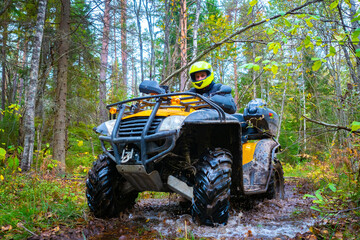 Man on a quad bike view from below. ATV is standing in the mud. ATV rides through the woods. Biker...
