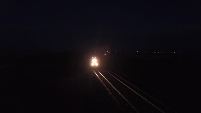 Freight train lights prairie railroad tracks on dark purple night