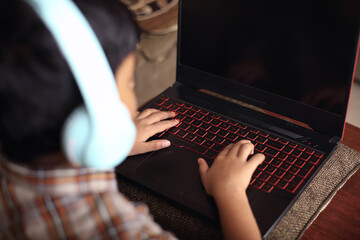 Portrait of Indian little boy using laptop while attending the online class at home
