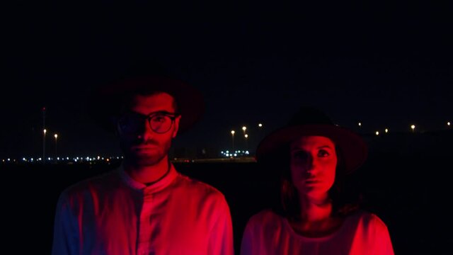 Hipster Man And Woman Staring Into Camera With Blue Light Shifting To Red - Closeup Shot