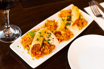 Close-up of tasty Moroccan lamb spring roll with harissa and couscous