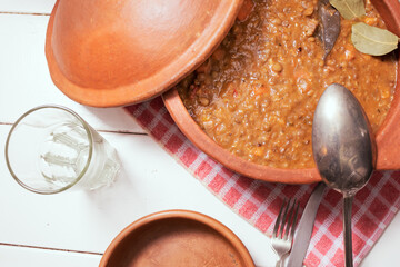 Clay pot with homemade lentil stew, tomato, Spanish chorizo, meat and potatoes.