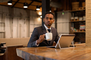 Young African businessman relaxing inside coffee shop