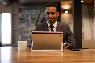Young African businessman using laptop computer at coffee shop