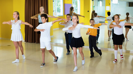 Diligent smiling positive children learn dance movements in dance class