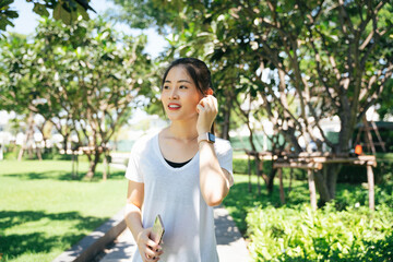 Sporty asian woman jogging on a path at park in summer season.