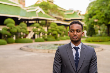 Portrait of young handsome African businessman thinking outdoors