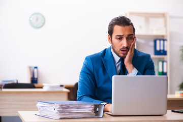 Young businessman employee unhappy with excessive work in the of