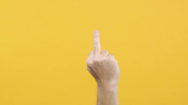 Man hand middle finger on yellow background.