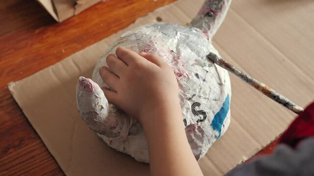 Boy painting a paper Viking helmet with silver paint. Carnival disguise.