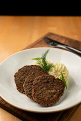 Roasted liver fritters with mashed potato on a wooden table in a wide restaurant plate, appetising photo for a menu