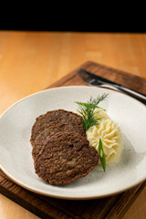 Roasted liver fritters with mashed potato on a wooden table in a wide restaurant plate, appetising photo for a menu