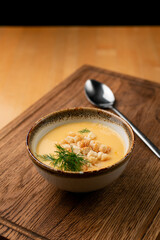 Creamy aroma corn soup with crunchy croutons, on wooden table with spoon aside, wooden table, side view
