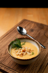 Creamy aroma corn soup with crunchy croutons, on wooden table with spoon aside, wooden table, side view