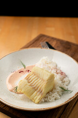 White fish fillet, roast with golden crust, laying on a pile of boiled rice, close up